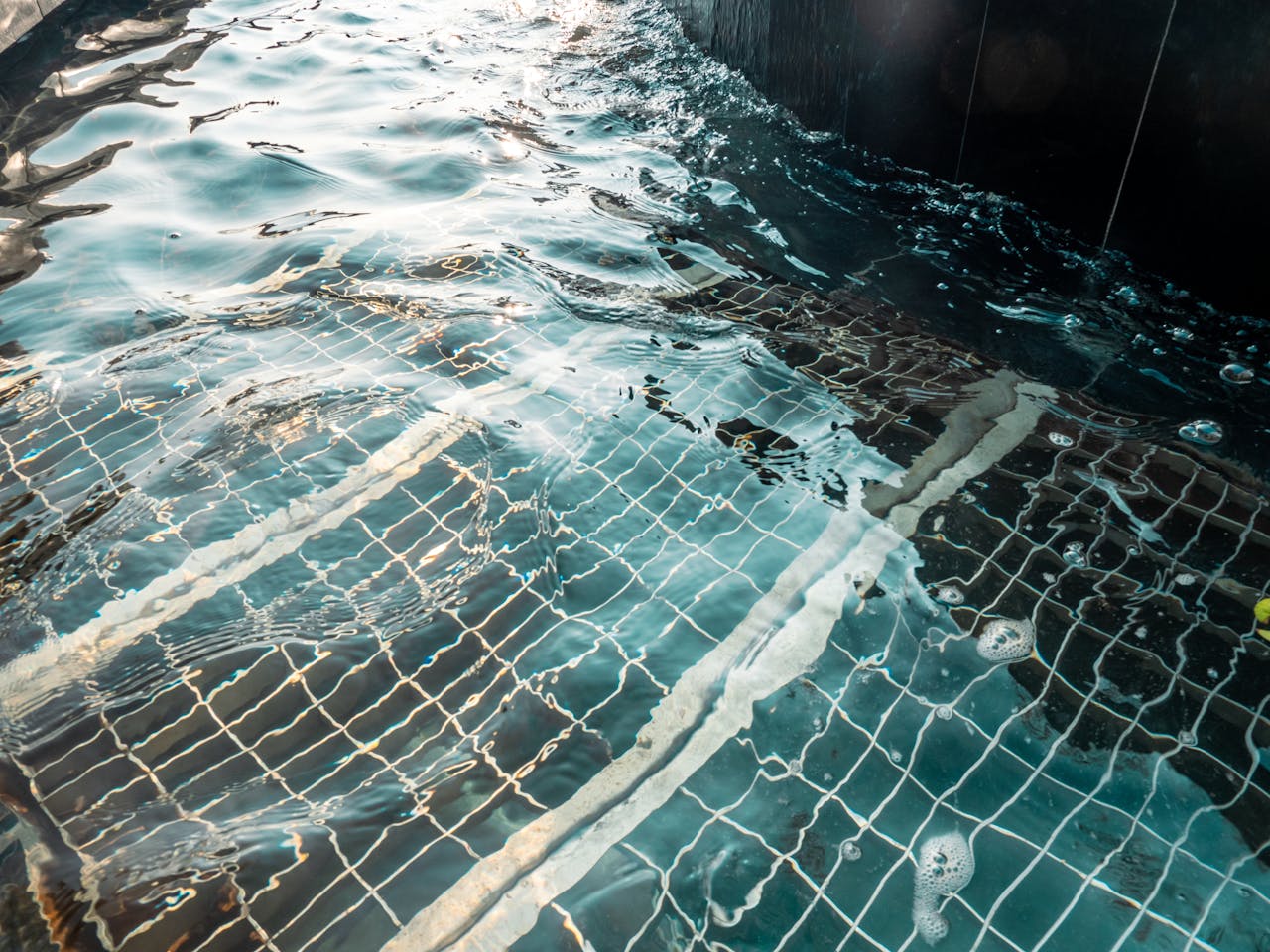 Peaceful reflections on a clear swimming pool surface, showcasing underwater tile patterns and gentle ripples.